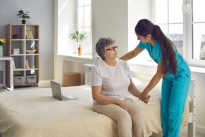 Caregiver helps an older resident sanitize hands in a clean assisted living common area.