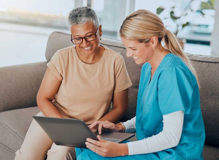 Older adult and family member reviewing a care assessment at a kitchen table with notes and medication list.